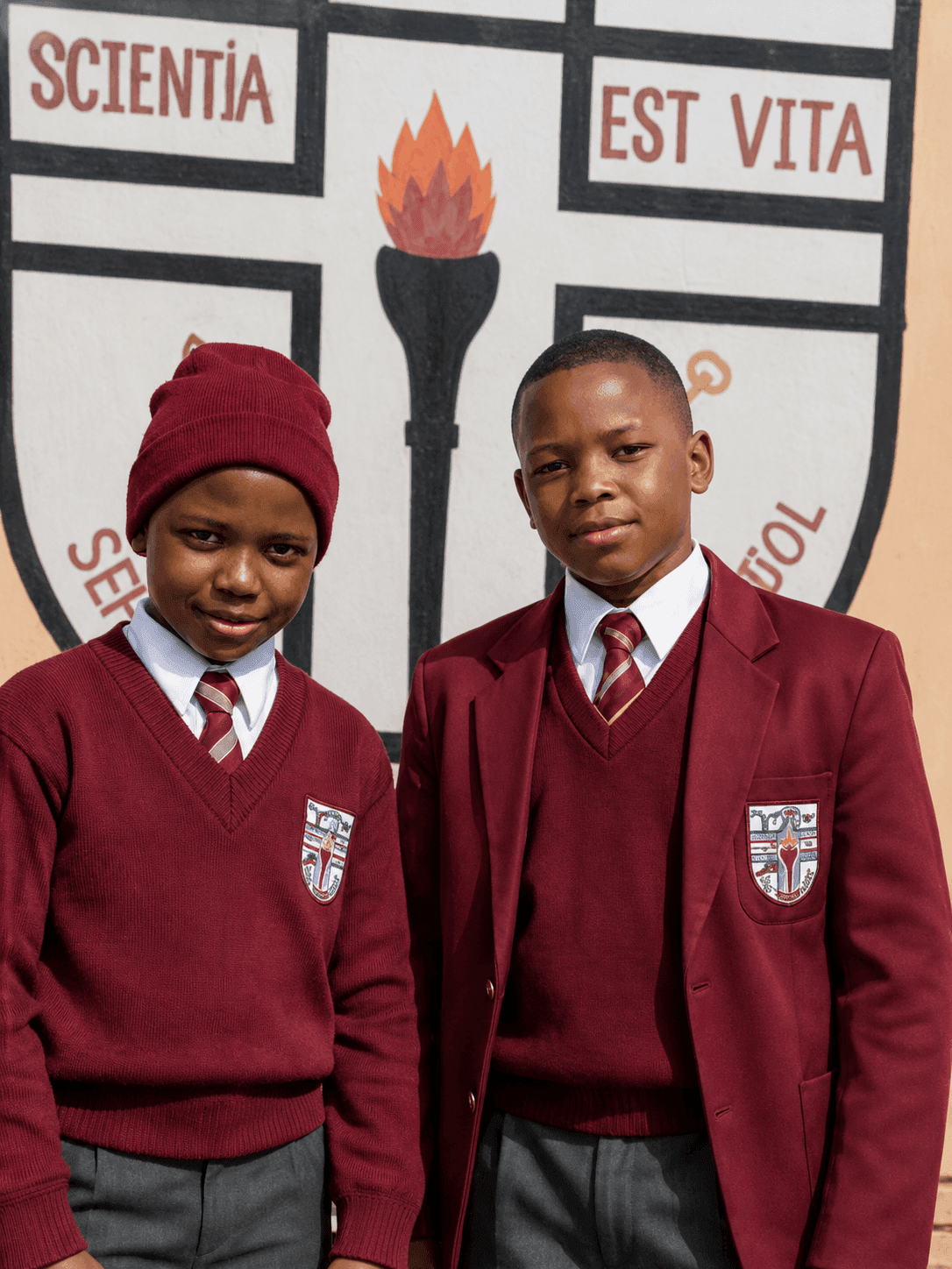 Two primary school learners in burgundy uniforms
